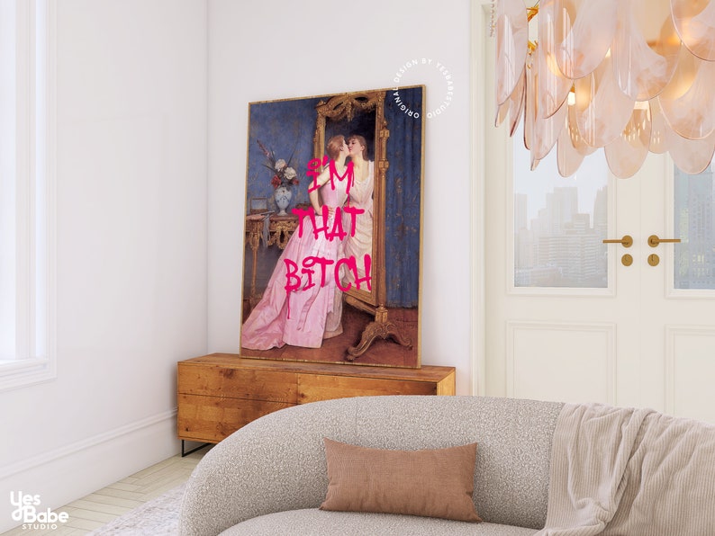 May include: A framed print of a vintage painting of two women in a room with a mirror. The woman in the foreground is wearing a pink dress and the woman in the mirror is wearing a white dress. The text "I'M THAT BITCH" is written in pink letters over the image.