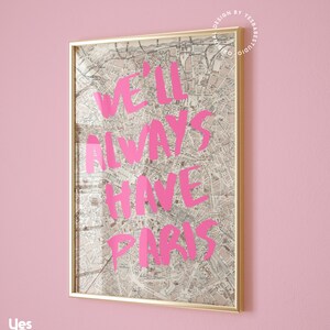 K&ouml;nnte beinhalten: Ein gerahmter Druck mit einer Vintage-Karte von Paris als Hintergrund. Die Worte "We'll Always Have Paris" sind in Pink &uuml;ber die Karte geschrieben.