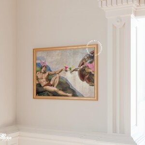 May include: A humorous parody of Michelangelo's "The Creation of Adam" painting, featuring two men in a similar pose, but with bunny ears and holding cocktails instead of touching fingers.