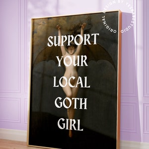 May include: A framed print with a dark background featuring a woman with wings, with the text "SUPPORT YOUR LOCAL GOTH GIRL" in white letters.