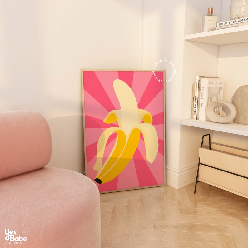 May include: A framed print of a yellow banana on a pink background with a radial pattern. The banana is peeled and the inside is visible. The print is in a wooden frame.
