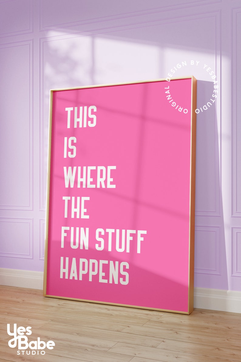 Puede incluir: P&oacute;ster rosa con marco dorado y texto blanco que dice "This is where the fun stuff happens". El p&oacute;ster est&aacute; colgado en una pared morada.