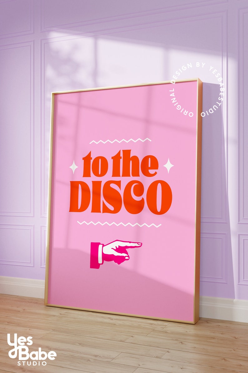 May include: A pink poster with a gold frame featuring the text "to the disco" in orange and white lettering with a pink pointing hand graphic. The poster is hanging on a purple wall.