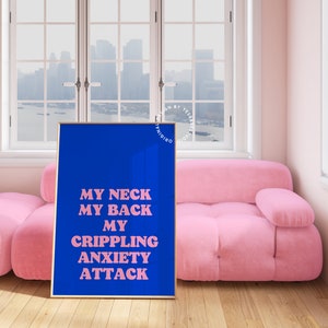 May include: A blue poster with pink text that reads "MY NECK MY BACK MY CRIPPLING ANXIETY ATTACK" hanging on a wall in a room with a pink sofa and a window with a city view.