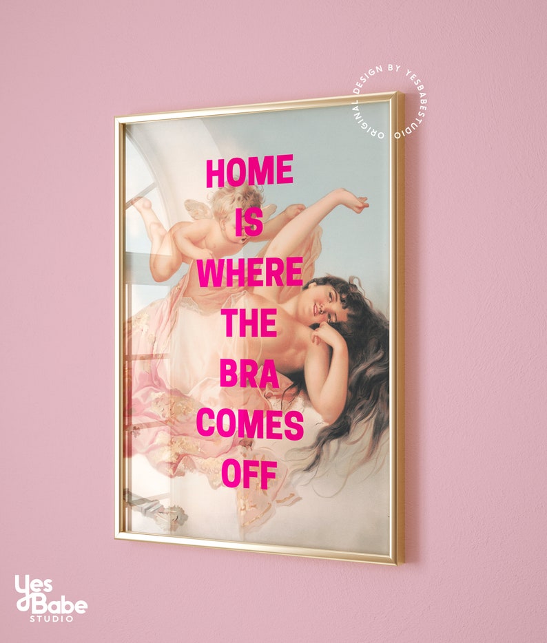 May include: A framed print with a gold frame and a painting of a woman with a cherub. The text "HOME IS WHERE THE BRA COMES OFF" is printed in pink on the painting.