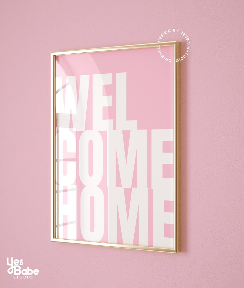 May include: A gold framed print with a pink background and white text that reads "WELCOME HOME".