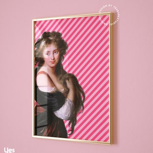 May include: A framed print of a woman with long brown hair wearing a white and black dress against a pink and white striped background. The frame is gold.