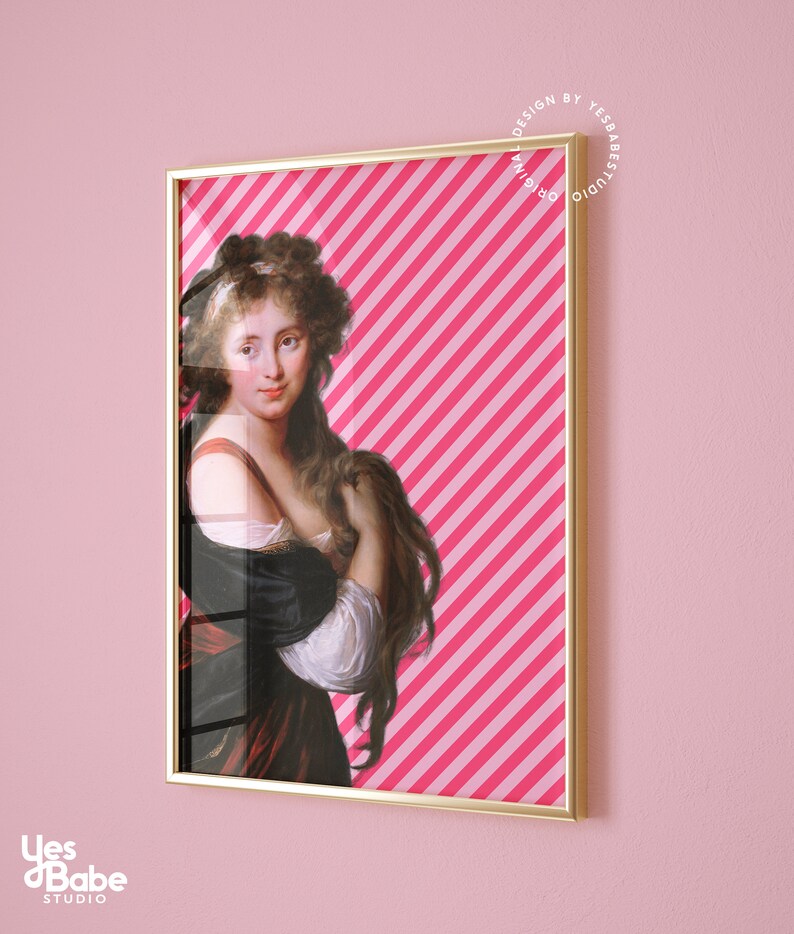 May include: A framed print of a woman with long brown hair wearing a white and black dress against a pink and white striped background. The frame is gold.