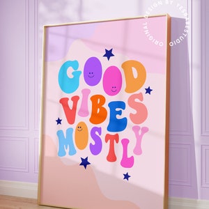 Op de afbeelding: Een roze en paarse abstracte achtergrond met de tekst "GOOD VIBES MOSTLY" in kleurrijke, omrande letters met smiley-gezichten. De letters zijn in een retro-stijl lettertype.