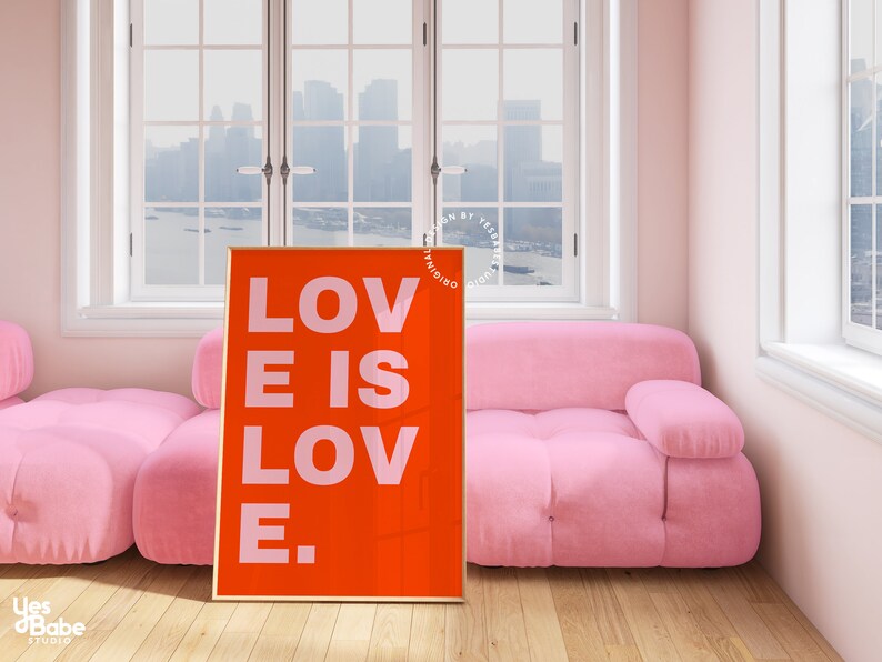 Może przedstawiać: Wydruk w ramie z czerwonym tłem i białym tekstem, kt&oacute;ry brzmi "LOVE IS LOVE." Wydruk wisi na ścianie w pokoju z r&oacute;żową sofą i oknem z widokiem na panoramę miasta.
