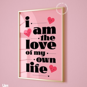 May include: Pink framed print with the text "i am the love of my own life" in black bold font. The text is interspersed with small pink hearts with smiley faces.
