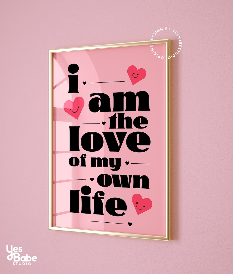 May include: Pink framed print with the text "i am the love of my own life" in black bold font. The text is interspersed with small pink hearts with smiley faces.