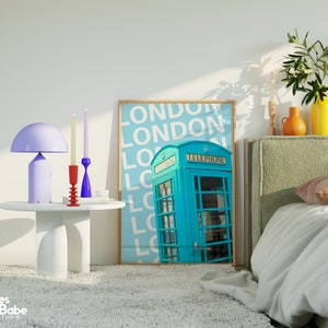 May include: A teal blue vintage-style telephone box with the word "TELEPHONE" printed on the front. The box is in front of a light blue background with the word "LONDON" repeated in white text.