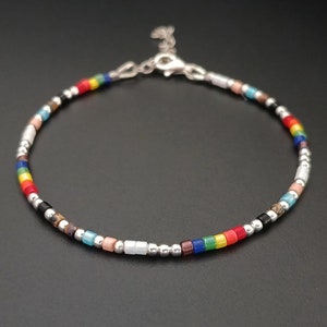 Könnte beinhalten: Ein farbenfrohes Perlenarmband mit silbernen Perlen und einem silbernen Verschluss. Das Armband zeigt einen Regenbogen aus Farben, darunter Rot, Orange, Gelb, Grün, Blau, Indigo und Violett.