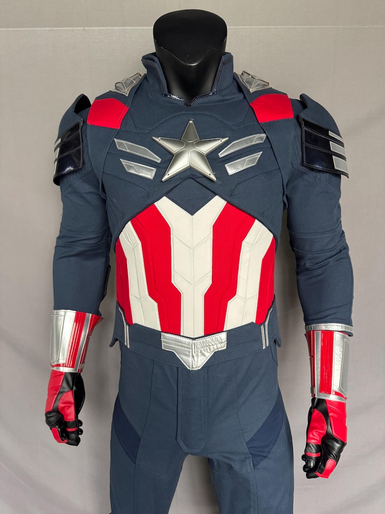 Puede incluir: Un traje de superh&eacute;roe azul y rojo con una estrella plateada en el pecho. El traje tiene un cintur&oacute;n plateado y detalles plateados en los brazos y las piernas.