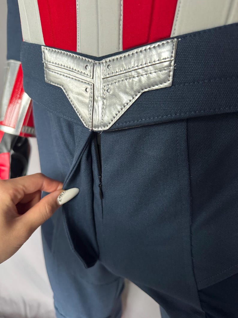 Puede incluir: Primer plano de un par de pantalones azules con una hebilla de cintur&oacute;n plateada. La hebilla del cintur&oacute;n tiene un dise&ntilde;o geom&eacute;trico con un borde cosido.