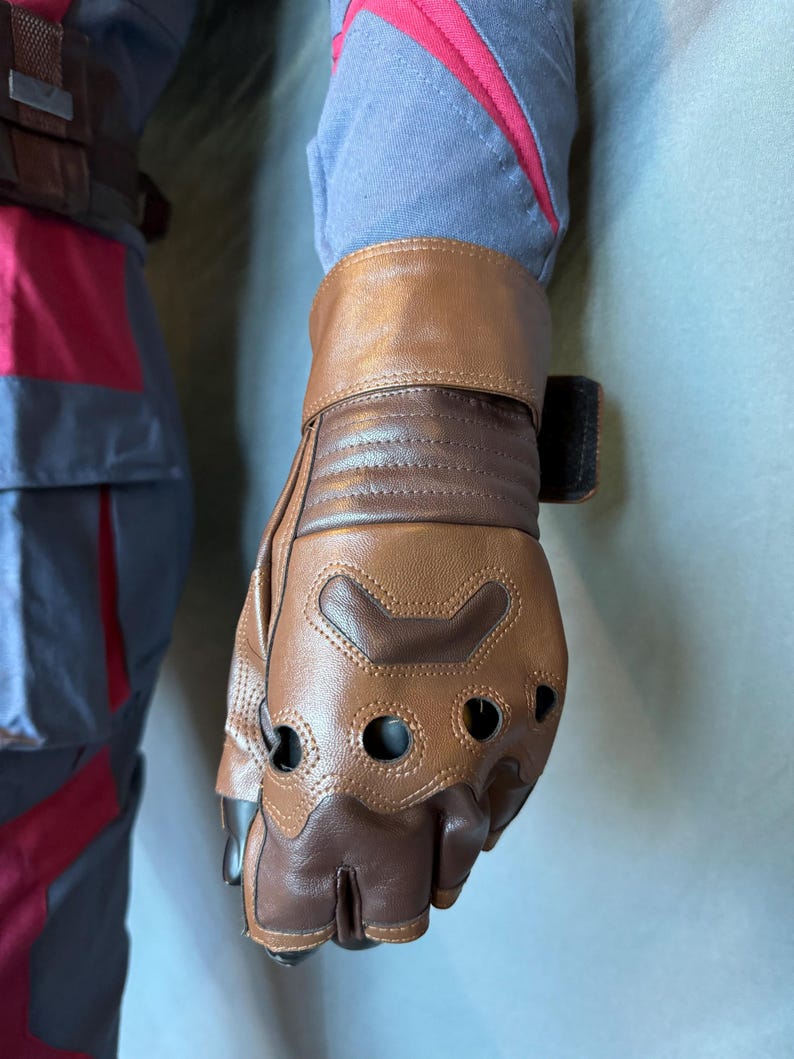 Puede incluir: Guantes de cuero marr&oacute;n con agujeros para los dedos y una correa de cuero marr&oacute;n en la mu&ntilde;eca. Los guantes tienen un dise&ntilde;o texturizado y est&aacute;n hechos de un material duradero.