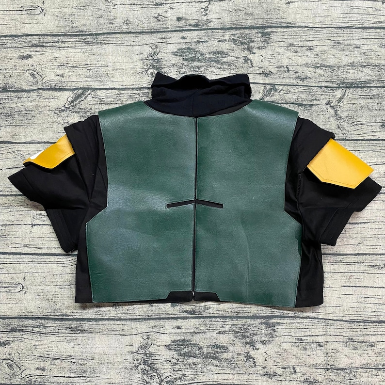 May include: A green and black costume vest with yellow shoulder pads. The vest has a black trim and a zipper in the back.