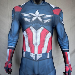 May include: A blue, red, and white Captain America costume displayed on a mannequin. The costume features a star emblem on the chest and red and white stripes on the torso. The sleeves and legs are blue with red and white accents.