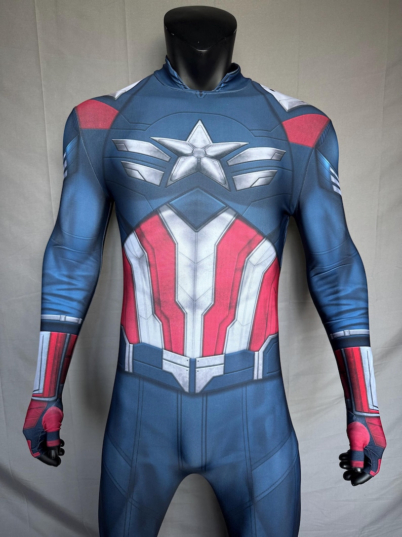 May include: A blue, red, and white Captain America costume displayed on a mannequin. The costume features a star emblem on the chest and red and white stripes on the torso. The sleeves and legs are blue with red and white accents.