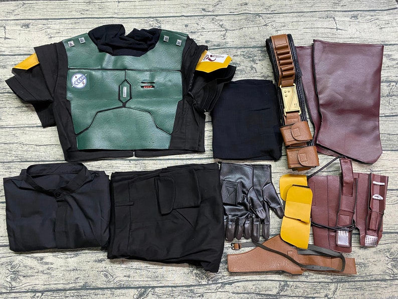 May include: A black and green costume with a variety of accessories, including a belt, gloves, and a pair of pants. The costume features a chest piece with a green and black design.