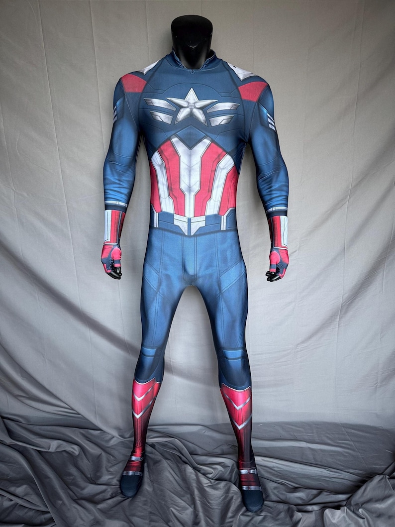 May include: A full-body Captain America costume. The blue suit features a white star on the chest, red and white stripes on the torso, and red accents on the arms and legs. The costume is displayed on a black mannequin.