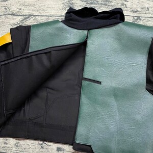 May include: A black and green jacket with a zipper closure. The jacket has a green leather panel on the front and a black fabric panel on the back. The jacket is unzipped, revealing the inside lining.