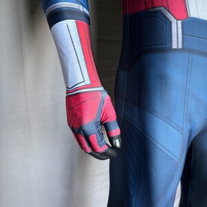 May include: A blue, red, and white superhero costume with a detailed design. The costume features a blue base with red and white accents on the arms and chest. The gloves are red and black.
