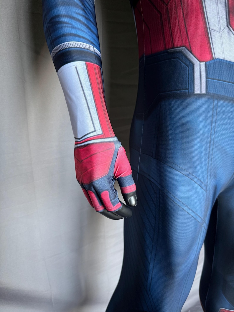 May include: A blue, red, and white superhero costume with a detailed design. The costume features a blue base with red and white accents on the arms and chest. The gloves are red and black.