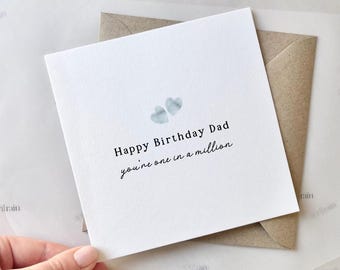 Könnte beinhalten: Eine weiße Karte mit zwei hellblauen Aquarellherzen und dem Text "Happy Birthday Dad you're one in a million".