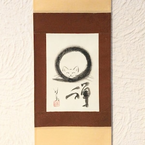 Peut inclure: Peinture sur rouleau japonaise représentant un chat minimaliste. L'œuvre d'art représente le visage d'un chat dans un cercle noir, avec une calligraphie japonaise en dessous. Le rouleau a une bordure marron et un fond beige.