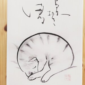 Könnte beinhalten: Leinwanddruck mit einer minimalistischen Tuschezeichnung einer schlafenden Katze. Die Katze ist zusammengerollt, mit schwarzen und grauen Streifen, vor einem weißen Hintergrund. Japanische Kalligraphie befindet sich darüber.
