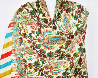 May include: A white shawl with a paisley and floral pattern in shades of red, blue, green, and yellow. The shawl has a striped border with red, yellow, and blue stripes.