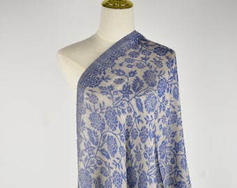 May include: A beige shawl with a blue floral pattern. The shawl is draped over a mannequin.