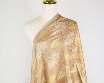 May include: A beige shawl with a gold and yellow paisley pattern. The shawl is draped over a white mannequin.