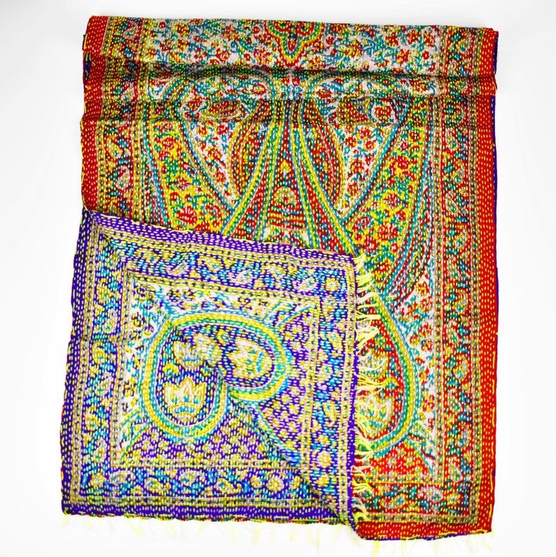 Puede incluir: Una colcha kantha de colores con estampado de paisley y borde rojo. La colcha est&aacute; doblada por la mitad y el estampado es visible en ambos lados.