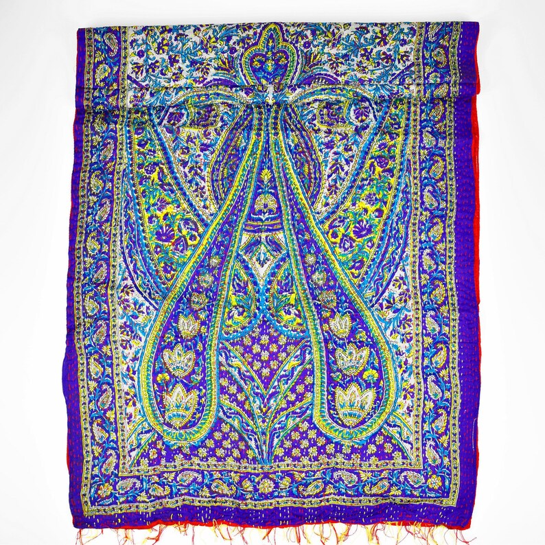 Puede incluir: Una bufanda de seda con estampado paisley morado y azul con borde rojo. La bufanda tiene un borde con flecos.