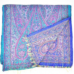 Puede incluir: Una bufanda de seda azul y p&uacute;rpura con estampado de paisley y flecos amarillos. La bufanda est&aacute; doblada por la mitad y el estampado es visible en ambos lados.