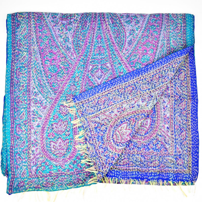 Puede incluir: Una bufanda de seda azul y p&uacute;rpura con estampado de paisley y flecos amarillos. La bufanda est&aacute; doblada por la mitad y el estampado es visible en ambos lados.