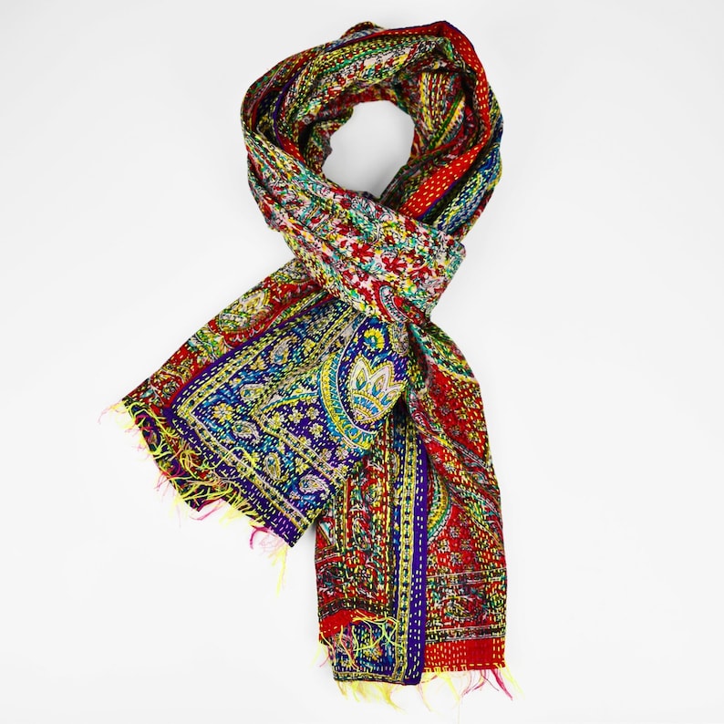 Puede incluir: Una bufanda de seda con estampado paisley rojo, verde, azul y amarillo con bordes con flecos.