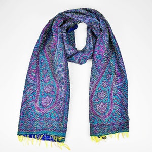Puede incluir: Una bufanda de seda azul y morada con estampado de paisley, costuras amarillas y flecos azules.