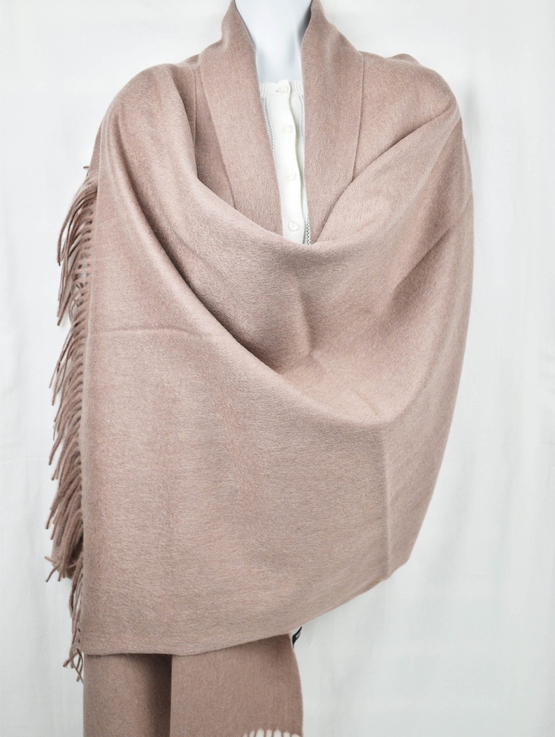 May include: A soft, light brown shawl with a fringe border. The shawl is made of a fine, delicate fabric and is perfect for adding a touch of elegance to any outfit.