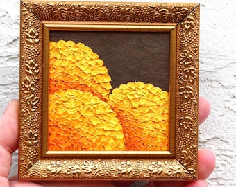 May include: A small framed painting of two yellow flower clusters against a dark brown background. The frame is gold with an ornate design.