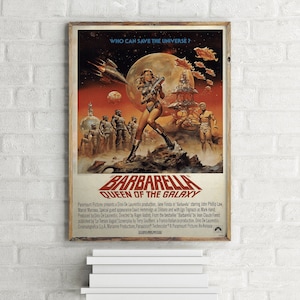 May include: A vintage film poster for the movie "Barbarella: Queen of the Galaxy" featuring Jane Fonda in a futuristic outfit holding a gun. The poster has a red, orange, and yellow colour scheme with a white background. The text "Who can save the universe?" is at the top of the poster.