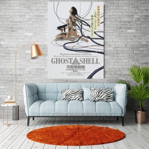 May include: A poster for the anime film "Ghost in the Shell" featuring a woman with long black hair and a robotic body. The poster is set against a white background with black wires and cables. The text on the poster reads "People love machines in 2029 A.D." and "Ghost in the Shell".