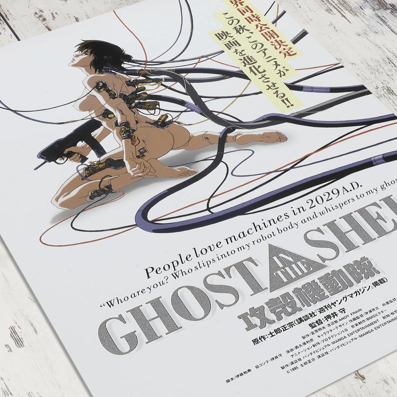 May include: A poster for the anime film "Ghost in the Shell" featuring a woman with a gun and wires connected to her body. The text on the poster reads "People love machines in 2029 A.D. "Who are you? Who slips into my robot body and whispers to my ghost..."  Ghost in the Shell:  攻殻機動隊"