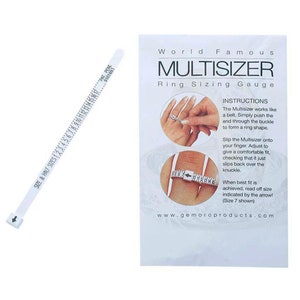 Peut inclure: Une jauge de mesure de bagues Multisizer blanche avec une échelle imprimée et une flèche, à côté d'une carte avec des instructions et le texte "World Famous Multisizer Ring Sizing Gauge". La jauge mesure les tailles de bagues.