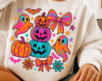 May include: White sweatshirt featuring a colorful Halloween design. The graphic includes stacked pumpkins, ghosts, bows, stars, bats, and flowers in vibrant shades of pink, orange, blue, and yellow. The sweatshirt has a crew neck.
