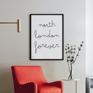 May include: A red armchair with black legs sits in a living room with a gold floor lamp, a white side table, and a framed print with the text "north london forever".