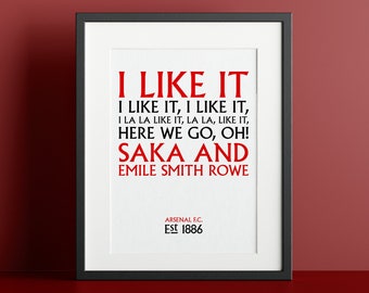 May include: A black framed print with a white background and red text. The text reads "I LIKE IT I LIKE IT, I LIKE IT, I LA LA LIKE IT, LA LA, LIKE IT, HERE WE GO, OH! SAKA AND EMILE SMITH ROWE ARSENAL F.C. Est 1886".
